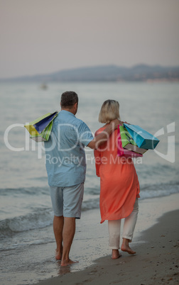 A middle aged couple walking down the sea coast barefoot