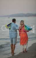 A middle aged couple walking down the sea coast barefoot