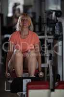 A middle aged woman in a gym on one of the training machines
