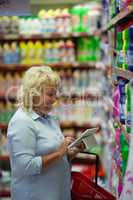 A middle aged woman with a tablet in a household section of a supermarket