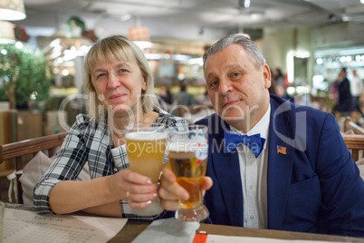 A portrait of a smiling middle aged couple with glasses of beer