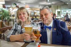 A portrait of a smiling middle aged couple with glasses of beer
