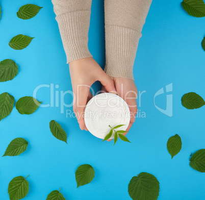 two female hands of a young girl with smooth skin and round jar