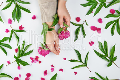 two hands of a young girl with smooth skin and a bouquet of red