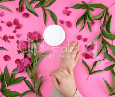 two hands of a young girl with smooth skin and a jar with thick