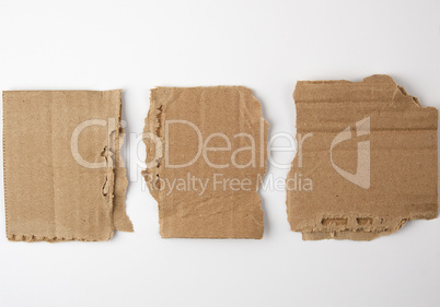 three pieces of torn brown paper on a white background