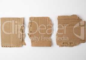 three pieces of torn brown paper on a white background