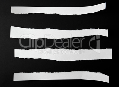 torn blank white paper strips against a black background