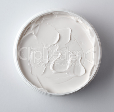 thick white cosmetic cream in a plastic jar, top view