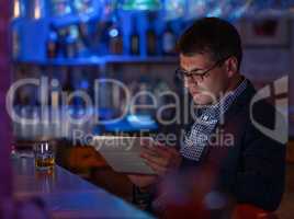 Businessman with tablet pc and whisky at the bar counter