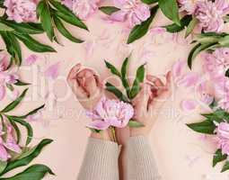 two hands of a young girl with smooth skin and a bouquet of pink