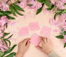 female hands glue empty paper pink stickers on the background wi