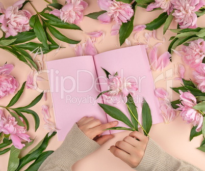 open notebook with empty pink pages and two female hands