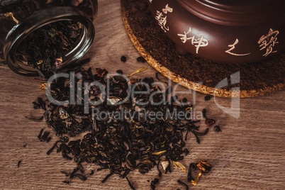Asian teapot on stand and jar with scattering of tea