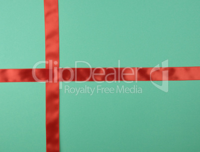 red satin ribbon cross to cross on green background