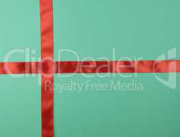 red satin ribbon cross to cross on green background