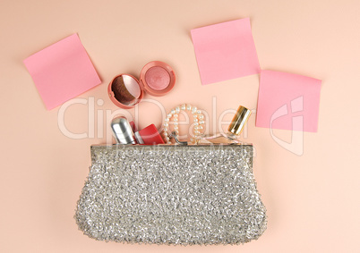 open silver clutch and cosmetics fell out of the middle