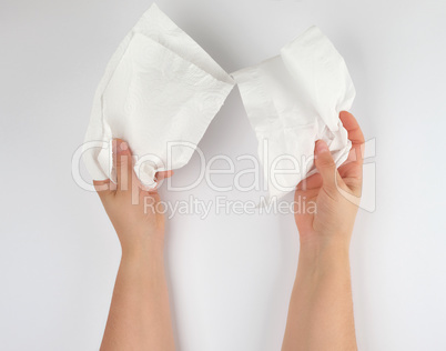 female hands holding a clean white paper napkin for face and bod