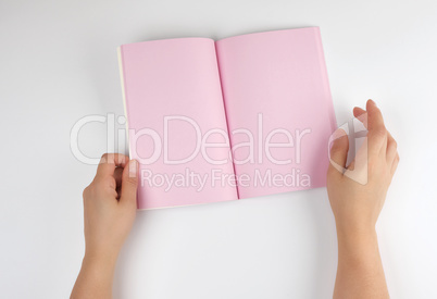 two female hands holding open notepad with clean pink sheets