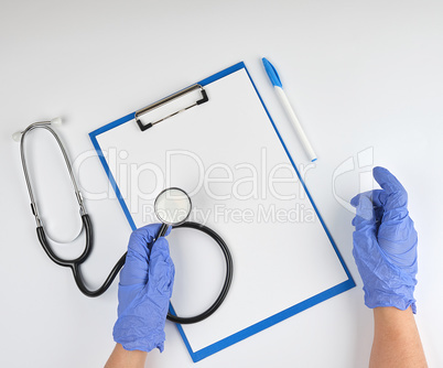 female hand in blue sterile gloves is holding a medical stethosc