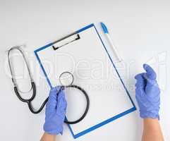 female hand in blue sterile gloves is holding a medical stethosc