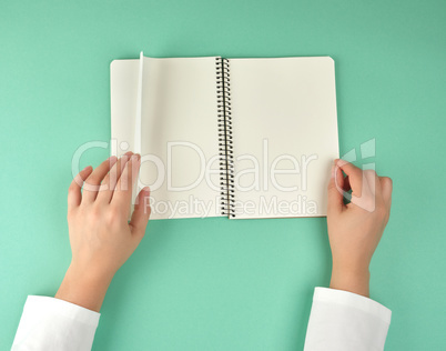 female hands hold open spiral notebook with clean white sheets