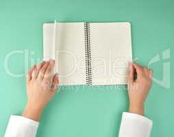 female hands hold open spiral notebook with clean white sheets