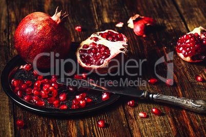 Whole and Opened Pomegranates on Metal Plate.