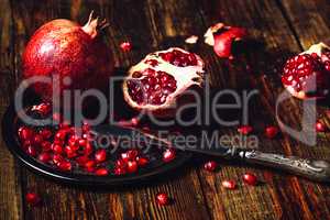 Whole and Opened Pomegranates on Metal Plate.