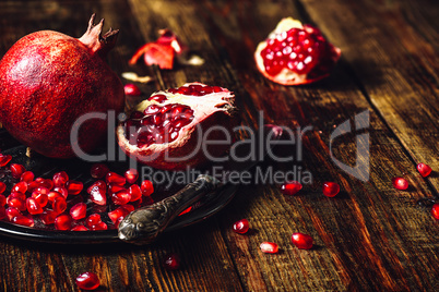 Whole and Opened Pomegranates on Plate.