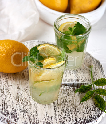 refreshing drink lemonade with lemons, mint leaves, lime in a gl