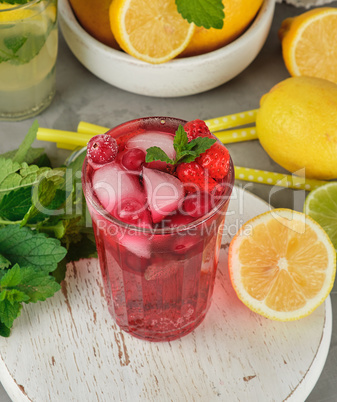red strawberry lemonade in a glass on a round white wooden board