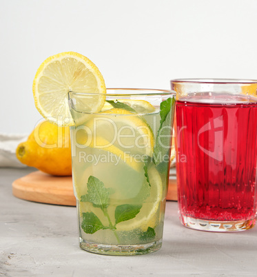 lemonade with lemons, mint leaves, lime in a glass and red berry