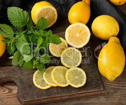 sliced yellow lemons on a brown wooden board, next to it lies a