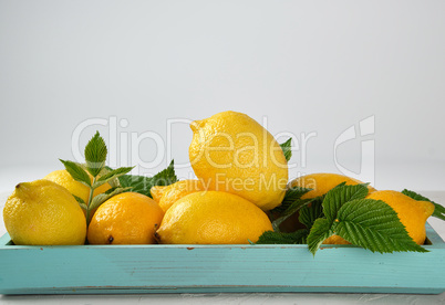 fresh ripe whole yellow lemons on a blue wooden board