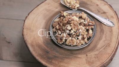 A bunch of walnuts on a silver platter rotates on a wooden stand