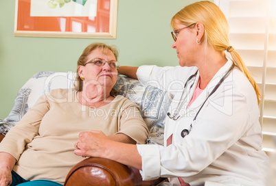 Happy Smiling Doctor or Nurse Talking to Senior Woman in Chair