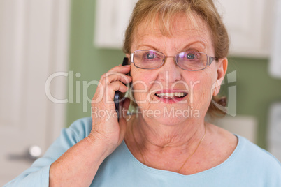 Happy Senior Adult Woman on Her Smart Cell Phone in Kitchen