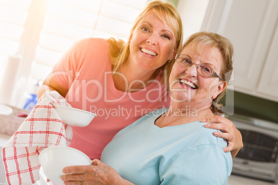 Portrait of Smiling Senior Adult Woman and Young Daughter At Sink