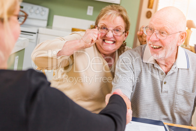 Senior Adult Couple Celebrating Over Documents at Home with Agent