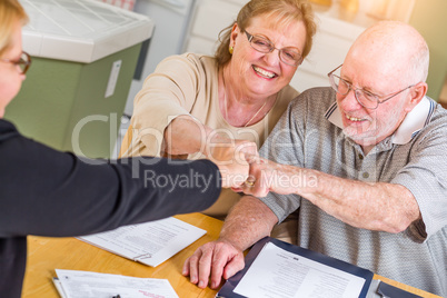 Senior Adult Couple Celebrating with Fist Bump Over Documents