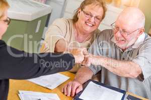 Senior Adult Couple Celebrating with Fist Bump Over Documents