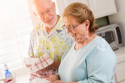Senior Adult Couple Having Fun Washing Dishes Together In Kitchen