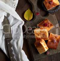 baked square pieces of pumpkin cheesecake on a wooden board