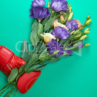 hand in a red boxing glove holding a bouquet of flowers Eustoma