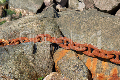 iron rusty ship chain in the midst of stones