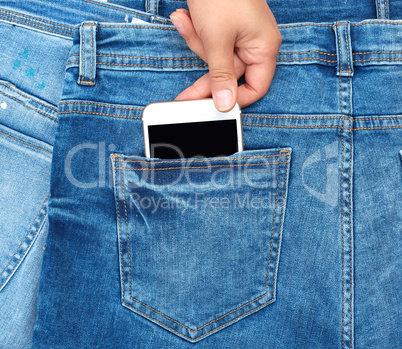 female hand pulls out of the back pocket of a blue jeans smartph