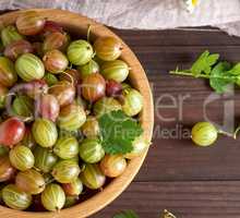 round wooden bowl with green and yellow gooseberries,