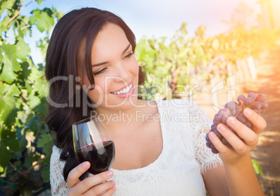 Beautiful Woman Holds Grapes and a Glass of Wine in The Vineyard