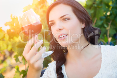 Beautiful Young Adult Woman Inspects Glass of Wine in The Vineyard